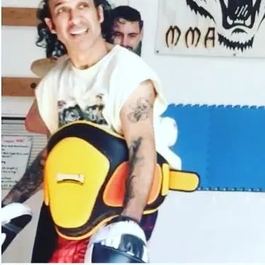 Coach Rex Pena strapped into a Muay Thai belly pad with a focus mitt ready